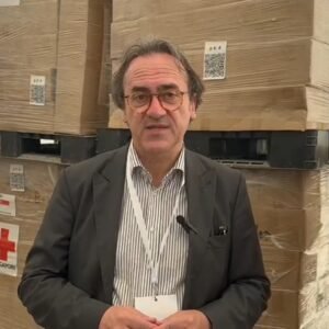 Deputado italiano Angelo Bonelli, entre caixas de ajuda humanitária para Gaza no galpão em Rafah