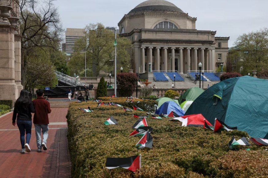 Students walk past a protest encampment on the main campus of Columbia University, organized by a group of students in support of Palestinians, during the ongoing conflict between Israel and the Palestinian Islamist group Hamas, in New York City, U.S., April 27, 2024. REUTERS/Caitlin Ochs